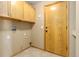Laundry room with tile flooring, wooden cabinets and a side door at 22815 E Progress Ave, Aurora, CO 80015