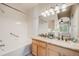 Bright bathroom featuring a double vanity, large mirror, and a shower-tub combo with tile surround at 13025 Grant Cir # A, Thornton, CO 80241