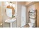 Bathroom features a pedestal sink, round mirror, and toilet with modern shelving unit for storage at 13025 Grant Cir # A, Thornton, CO 80241