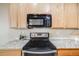 Close-up of the kitchen featuring stainless steel stove with black cooktop and wooden cabinets and granite countertops at 13025 Grant Cir # A, Thornton, CO 80241