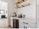 A stylish bar area featuring light wood cabinets, marble countertops, a wine fridge, and open shelving at 2900 S Adams St, Denver, CO 80210
