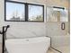 Modern bathroom featuring a freestanding tub, marble walls, a glass shower, and sleek black fixtures at 2900 S Adams St, Denver, CO 80210