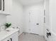 Well-lit laundry room with patterned tile flooring, white cabinets, countertop space, and modern black hardware at 2900 S Adams St, Denver, CO 80210