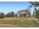 Backyard with manicured lawn, mature trees, retaining wall, and the home's two-story back exterior at 3174 Soaring Eagle Ln, Castle Rock, CO 80109