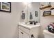 Well-lit bathroom with a modern vanity, mirror, and open shelving for storage and decor at 21038 E Quincy Pl, Aurora, CO 80015