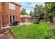 Well-manicured backyard featuring a patio, lush lawn, brick exterior, and mature trees, ideal for outdoor gatherings at 1332 S Lafayette St, Denver, CO 80210