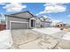 Gray house with a two-car garage and snowy driveway at 1546 Farmstead St, Brighton, CO 80601