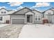 Gray exterior house with a two-car garage and snowy front yard at 1546 Farmstead St, Brighton, CO 80601