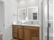 Bright bathroom featuring double vanity, framed mirrors, and glass-enclosed shower at 6153 N Ceylon St # 307, Denver, CO 80249