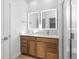 Bright bathroom featuring double vanity, framed mirrors, and glass-enclosed shower at 6153 N Ceylon St # 307, Denver, CO 80249