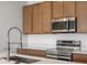 Kitchen area featuring stainless steel appliances, wood cabinets, and light countertops at 6153 N Ceylon St # 307, Denver, CO 80249