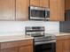 Close-up of modern stainless steel stove and oven under matching microwave, next to wooden cabinets at 6153 N Ceylon St # 307, Denver, CO 80249