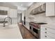 Lovely white kitchen with stone backsplash and stainless steel appliances and range at 16227 Pikes Peak Dr, Broomfield, CO 80023