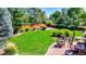 Lush green backyard featuring a patio with dining set and manicured garden providing an ideal space for relaxation at 3850 S Willow Way, Denver, CO 80237