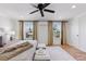 Primary bedroom with wood floors, a neutral bed with matching stools and curtains, and black ceiling fan at 3850 S Willow Way, Denver, CO 80237