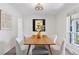 Dining room with a light fixture above a wood table and four white chairs, next to a window at 3850 S Willow Way, Denver, CO 80237
