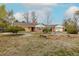 Charming single-story brick home with well-maintained landscaping and mature trees under a partly cloudy sky at 1345 Laredo St, Aurora, CO 80011