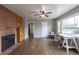 Bright living room with a brick accent wall, hardwood floors, a ceiling fan, and a large picture window at 1345 Laredo St, Aurora, CO 80011