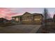 Charming home featuring a stone facade, two-car garage, and a covered front porch under a colorful evening sky at 6045 High Timber Cir, Castle Rock, CO 80104