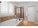 Bright bathroom featuring a soaking tub with tile surround and a glass-enclosed shower stall, enhanced by natural light at 6135 S Paris St, Englewood, CO 80111