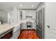 Well-equipped kitchen with white cabinets, stainless steel appliances, a farmhouse sink, and a marble backsplash at 6135 S Paris St, Englewood, CO 80111