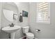 Stylish powder room with a pedestal sink, a round mirror, and window with plantation shutters at 6135 S Paris St, Englewood, CO 80111