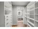 Bright walk-in closet featuring custom shelving and a view of an ensuite bathroom with modern fixtures and a wood floor at 6135 S Paris St, Englewood, CO 80111