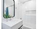 Bright bathroom featuring white tile, a modern sink, a black framed mirror, and a shower with a large shower head at 6088 S Lakeview St, Littleton, CO 80120