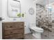 Modern bathroom featuring a wood vanity, decorative mirror, toilet, and a shower with decorative grey and white tile at 6088 S Lakeview St, Littleton, CO 80120