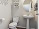 Stylish half-bathroom featuring a pedestal sink, decorative mirror, floating shelves, and modern fixtures at 6491 N Danube St, Denver, CO 80249