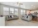 Open-concept living room with neutral tones, large windows, and modern ceiling fan at 6491 N Danube St, Denver, CO 80249