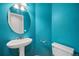 Stylish half bathroom with a pedestal sink, toilet, and vivid blue walls at 18121 E Adriatic, Aurora, CO 80013