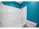 Bright bathroom featuring turquoise walls, white tiled bathtub with gold fixtures, and a toilet at 18121 E Adriatic, Aurora, CO 80013