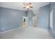 Large bedroom with blue walls and neutral carpet has a ceiling fan and access to a bathroom at 18121 E Adriatic, Aurora, CO 80013
