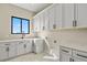 Bright laundry room with storage cabinets, granite counters, stainless steel appliances, and tile flooring at 16250 Kenosha St, Brighton, CO 80603