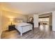 A bright bedroom with hardwood floors features a queen bed and access to another room upstairs at 14193 E Radcliff Cir, Aurora, CO 80015