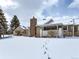 Snow covered backyard showing home's architectural details like brick chimney and attached patio at 13908 E Linvale Pl, Aurora, CO 80014