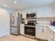 Modern kitchen featuring stainless steel appliances, white cabinetry, and ample counter space at 13908 E Linvale Pl, Aurora, CO 80014