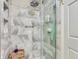 Walk-in shower with marble tile, a rainfall shower head, and built-in shelving at 13908 E Linvale Pl, Aurora, CO 80014