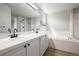 Neutral-toned bathroom featuring double sinks, a large mirror, and a soaking tub at 5934 Kingsfield St, Castle Rock, CO 80104
