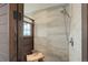 Modern shower featuring neutral tile, a rainfall shower head, and a unique wood framed glass door at 9537 Chesapeake St, Highlands Ranch, CO 80126