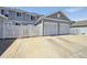 Exterior view of an attached two-car garage with white doors, driveway, and white picket fence at 5786 Biscay St, Denver, CO 80249