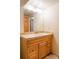 Bathroom featuring a wood cabinet, tan tile countertop, and large mirror with decorative lighting at 1055 S Clayton Way, Denver, CO 80209