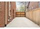 Long concrete driveway leading to a wooden gate and the back of the brick home at 1055 S Clayton Way, Denver, CO 80209