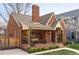 Inviting brick home featuring a covered front porch and manicured landscaping at 1055 S Clayton Way, Denver, CO 80209