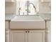 Close-up of a farmhouse sink with elegant faucet, bright lighting, and classic white cabinetry below at 1055 S Clayton Way, Denver, CO 80209