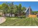Landscaped front yard with mature trees frames a classic brick home with attached two-car garage at 9929 W Fairview Ave, Littleton, CO 80127