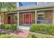 Charming brick home features a covered front porch and bright red front door with a decorative wreath at 9929 W Fairview Ave, Littleton, CO 80127