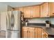 Spacious kitchen boasts stainless steel refrigerator, warm wood cabinets, and functional countertop space at 9929 W Fairview Ave, Littleton, CO 80127