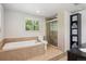 Bright bathroom featuring a soaking tub, tiled shower, and vanity with large window at 2865 Newland St, Wheat Ridge, CO 80214